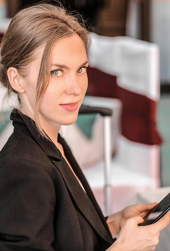 jeune femme avec une veste elle tient son téléphone et nous regarde